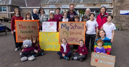 The whole Logiealmond school community — children, parents and teachers — outside the school holding hand-made signs