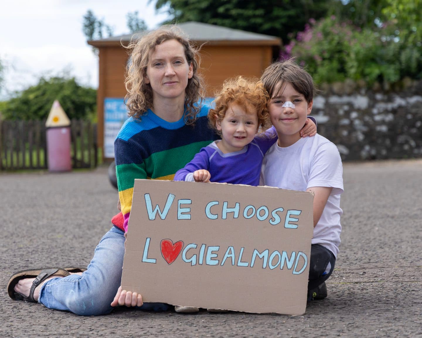 A mum and her children with a “We choose Logiealmond” sign